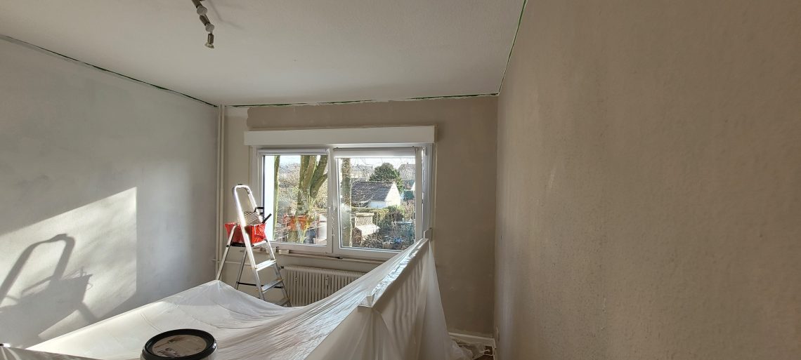 Zimmer während der Renovierung Wände sind vorgestrichen, Möbel abgedeckt