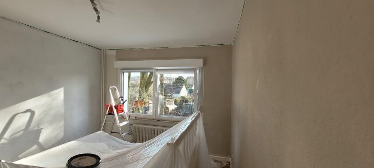 Zimmer während der Renovierung Wände sind vorgestrichen, Möbel abgedeckt
